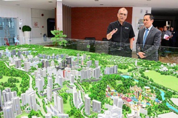 Khairil (left) explaining the project to Johor Baru Central Municipal Council president Dr Badrul Hisham Kassim. Laid out before them is the scale model of Medini Iskandar Puteri. (Photo from The Star)